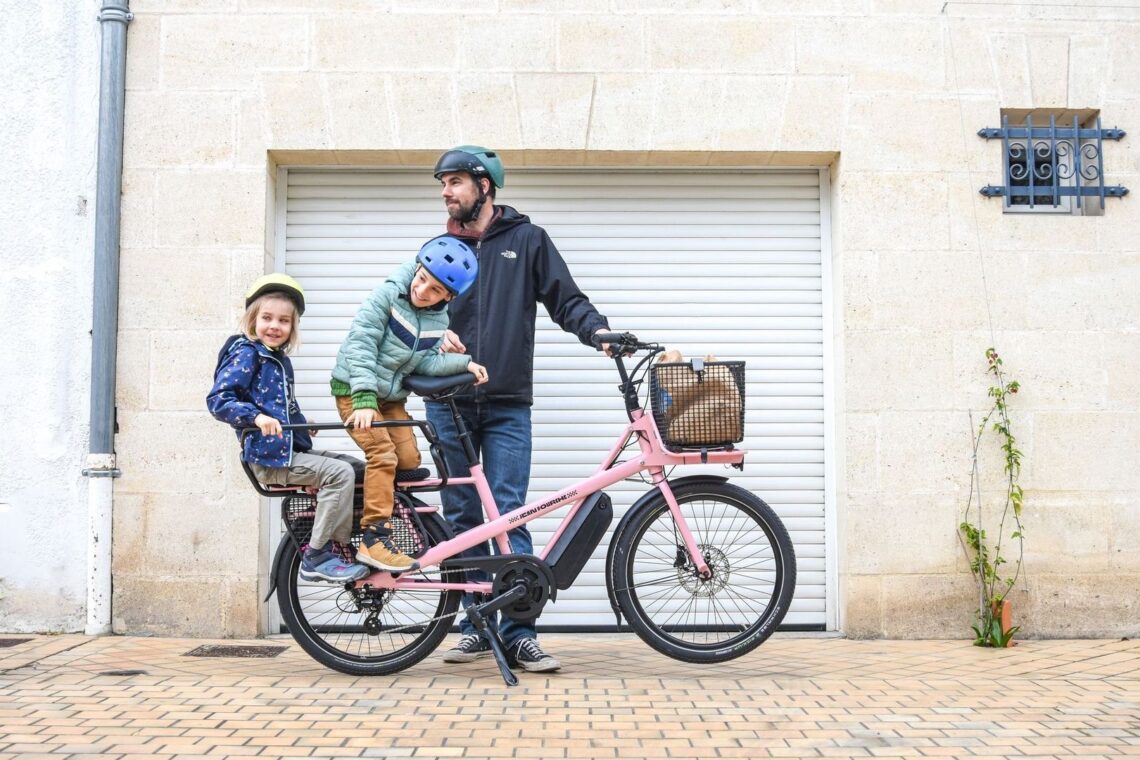 Familj med två barn på en rosa eldriven lastcykel