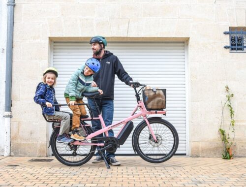 Familj med två barn på en rosa eldriven lastcykel