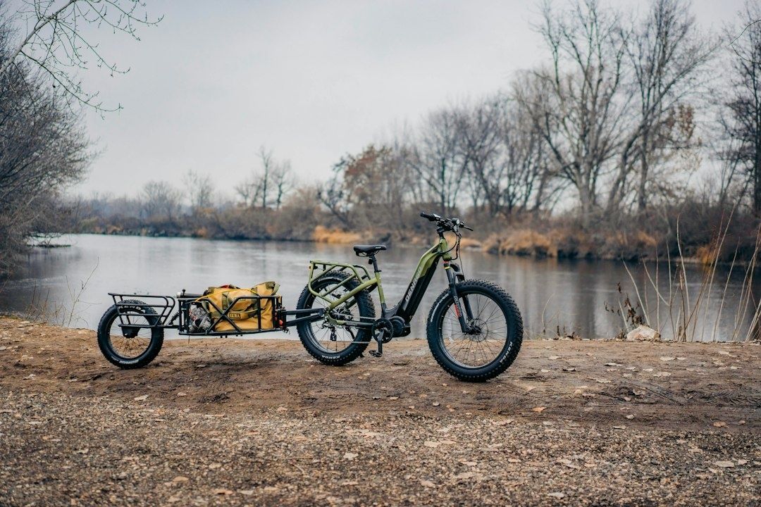 Elassisterad lastcykel med släpvagn vid en å i höstlandskap